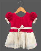 Detailed view of a kid's festive outfit with puff sleeves, intricate neck embroidery, and a pleated floral brocade skirt.