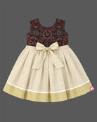 Little one wearing Ajrakh print peter pan collar frock with waist rosette detail and Kasavu border