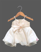 Off-white satin and organza party frock for baby girls featuring a large satin rose, embroidered leaf detail, and pearl embellishments