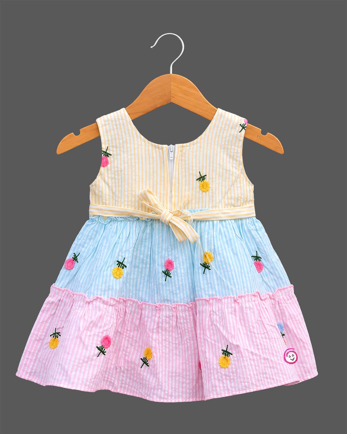 Sleeveless striped tiered frock with floral embroidered motifs and decorative shoulder applique accents.