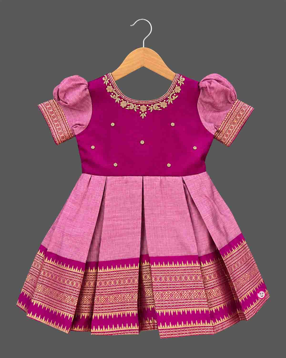 Girls silk cotton frock featuring embroidered round neckline, puff sleeves with zari trim, and pleated skirt.