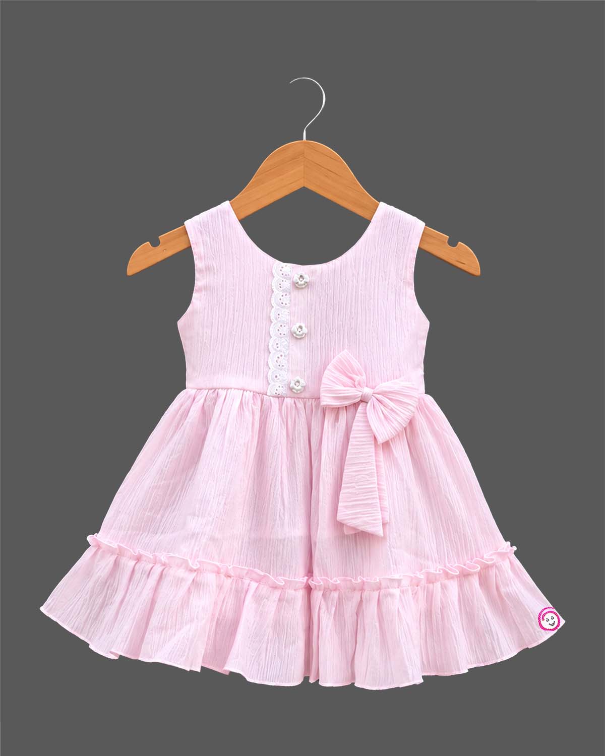 Sleeveless textured crinkle cotton frock with waist bow accent, lace trim, and tiered ruffle hemline for girls.