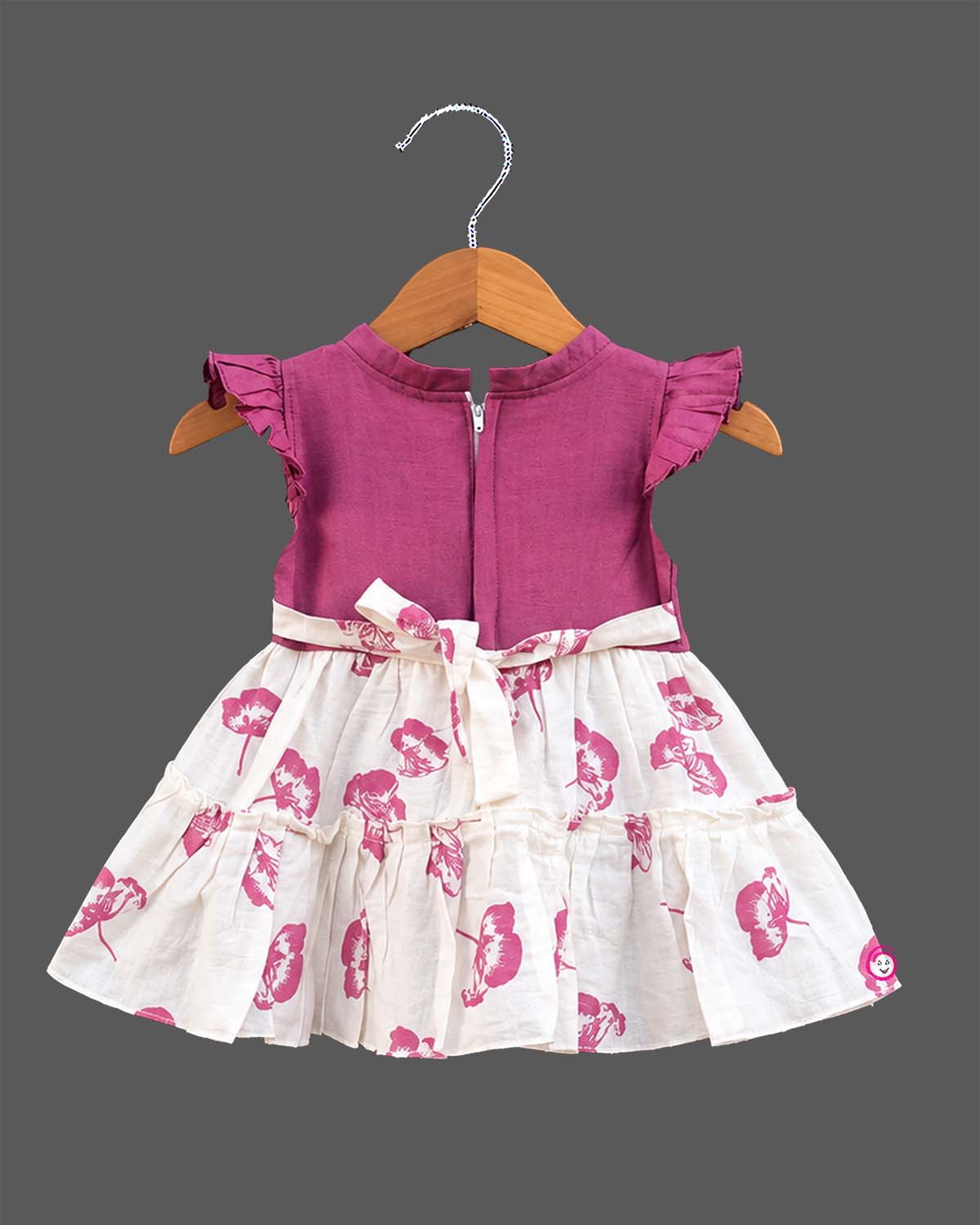 Toddler girl floral tiered frock with ruffled flutter sleeves, waist bow accent, and tiered flared skirt.