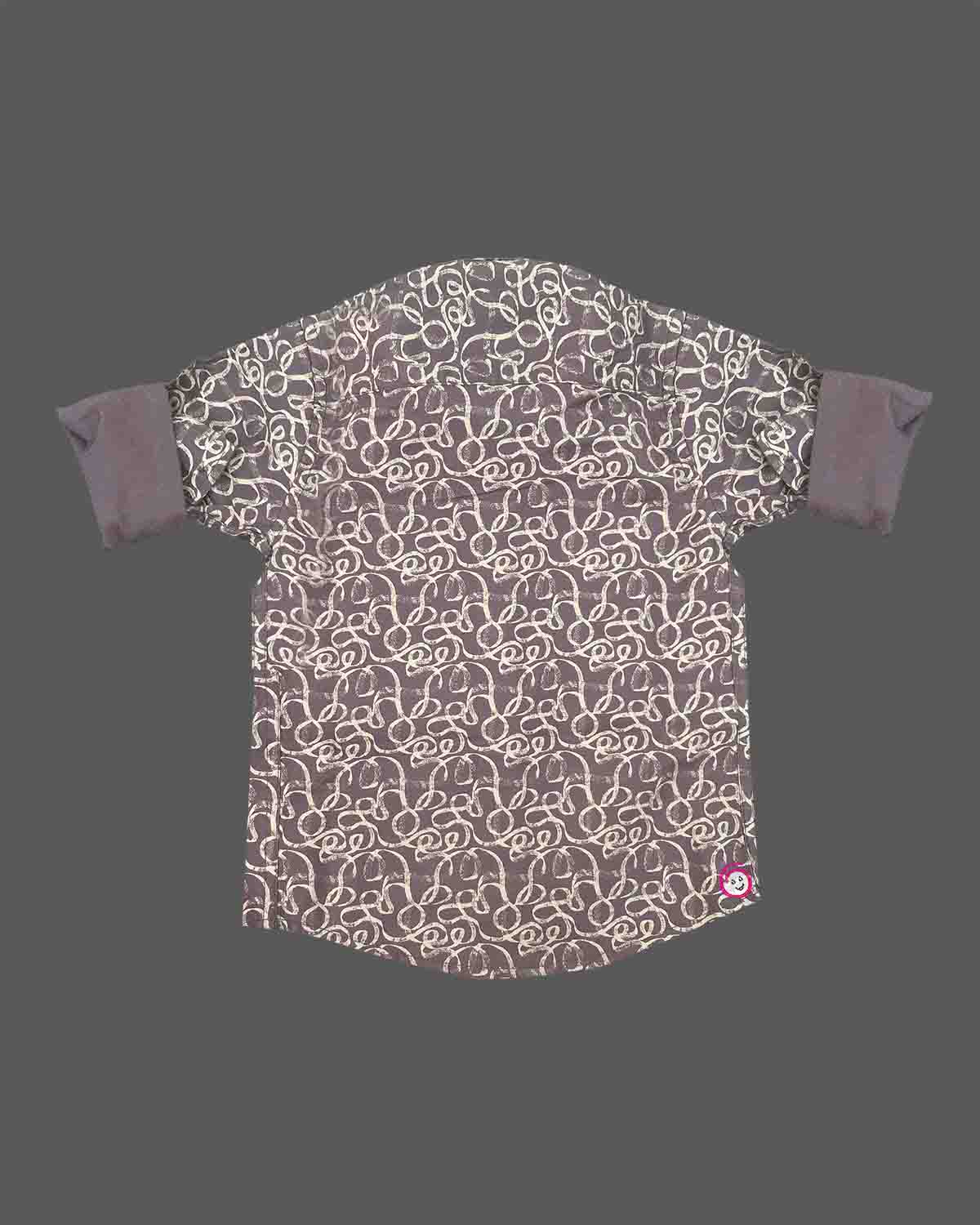 Front view of a printed collared shirt for boys with rolled-up cuffs and button closures on a neutral background.
