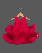 Voluminous party frock for little princess featuring a large statement rosette bodice and heavily ruffled tiered net skirt displayed on a hanger.