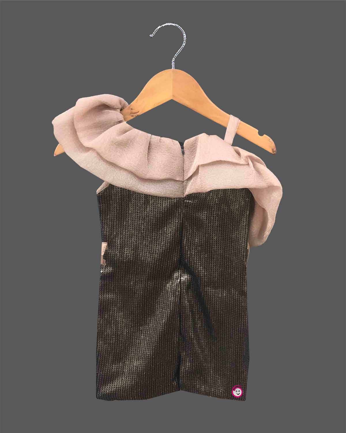 One shoulder girls toddler sequin party dress with light brown shoulder ruffle, black sequin body, and a black rose detail, hanging on a wooden hanger against a dark grey background, with a small OPUS RKID logo in the corner.