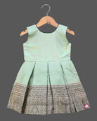 Infant  cotton silk frock in pastel mint green and dark bottle green with attached jacket style design, leaf embroidery, front tie-up tassels, and a traditional gold zari border