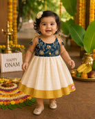Young princess wearing shoulder tie-up brocade yoke frock with Kasavu pleated skirt for Onam
