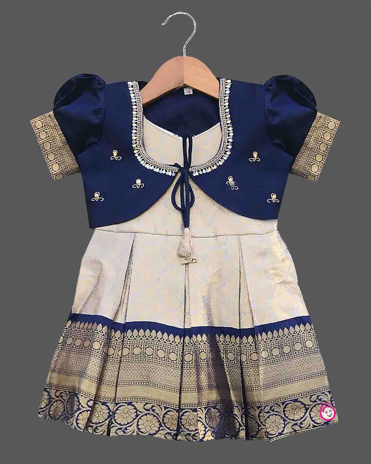 Infant silk cotton frock in cream and navy blue with attached jacket style design, front tie-up tassels, and a traditional heavy gold zari border