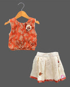 Sleeveless printed blouse adorned with a floral brooch paired with a box-pleated skirt for young girls
