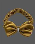Mustard gold satin party frock for girls featuring an oversized front bow with rhinestone embellishment and flared pleats.
