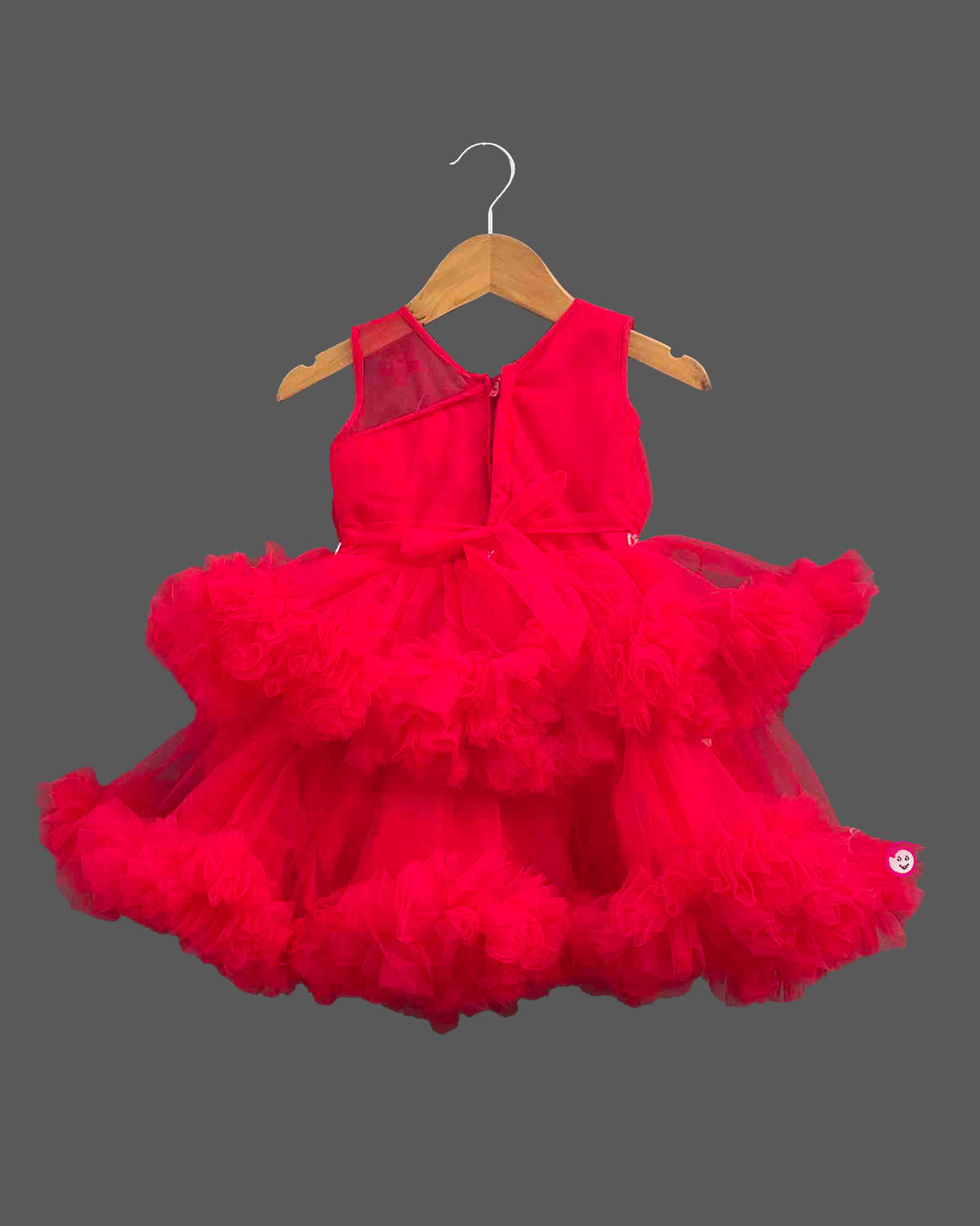 Sleeveless net ruffle baby party wear dress with high-low hemline and floral chest applique.