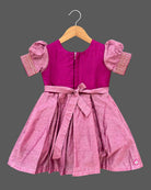 Girls silk cotton frock featuring embroidered round neckline, puff sleeves with zari trim, and pleated skirt.