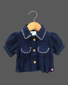 Stylish two-piece set for baby girls featuring a collared short-sleeve top with contrast stitch trim and matching embroidered pants with tassel details on a hanger.