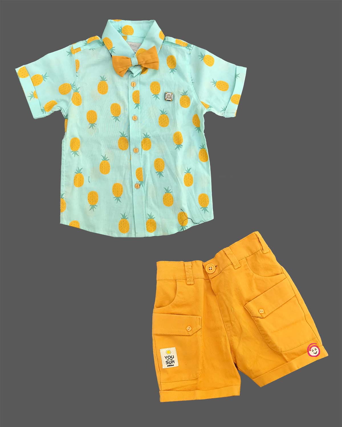 Boys attire featuring a tropical pattern button-down shirt, cargo style shorts, matching neck bow, and adjustable floral motif suspenders.