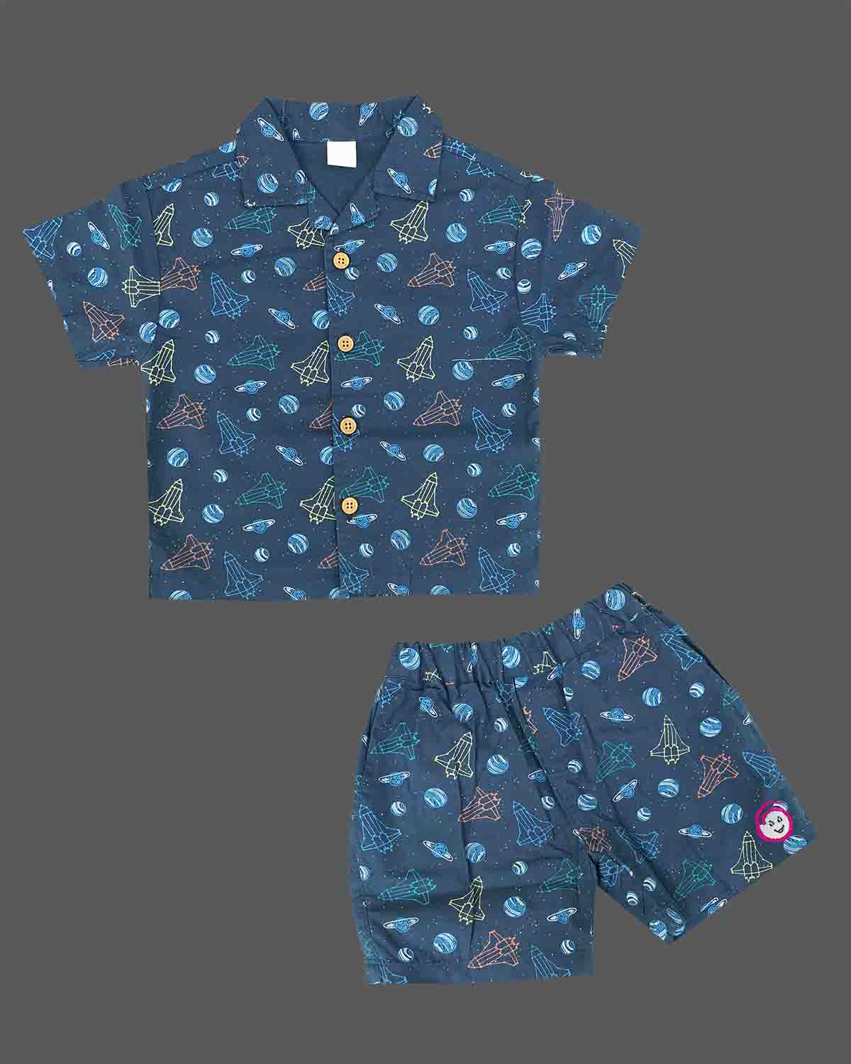 Young prince wearing space rocket patterned Cuban collar button shirt with matching elastic waistband shorts ensemble.