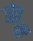 Young prince wearing space rocket patterned Cuban collar button shirt with matching elastic waistband shorts ensemble.