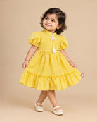 Infant yellow cotton frock with puff sleeves and tassels for family picnic