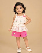 Cream tiered top with pink floral embroidery and bright pink shorts baby girl top and shorts set for summer vacations, playdates, and park outings