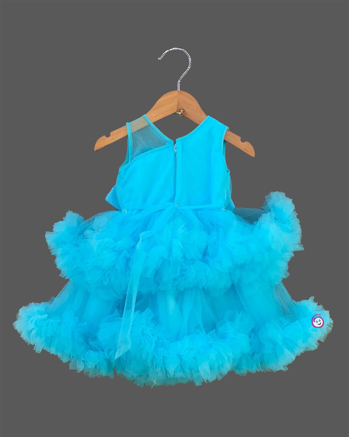 Glittering embellished flower applique party frock for little princess with ruffled high-low net skirt displayed on a wooden hanger.