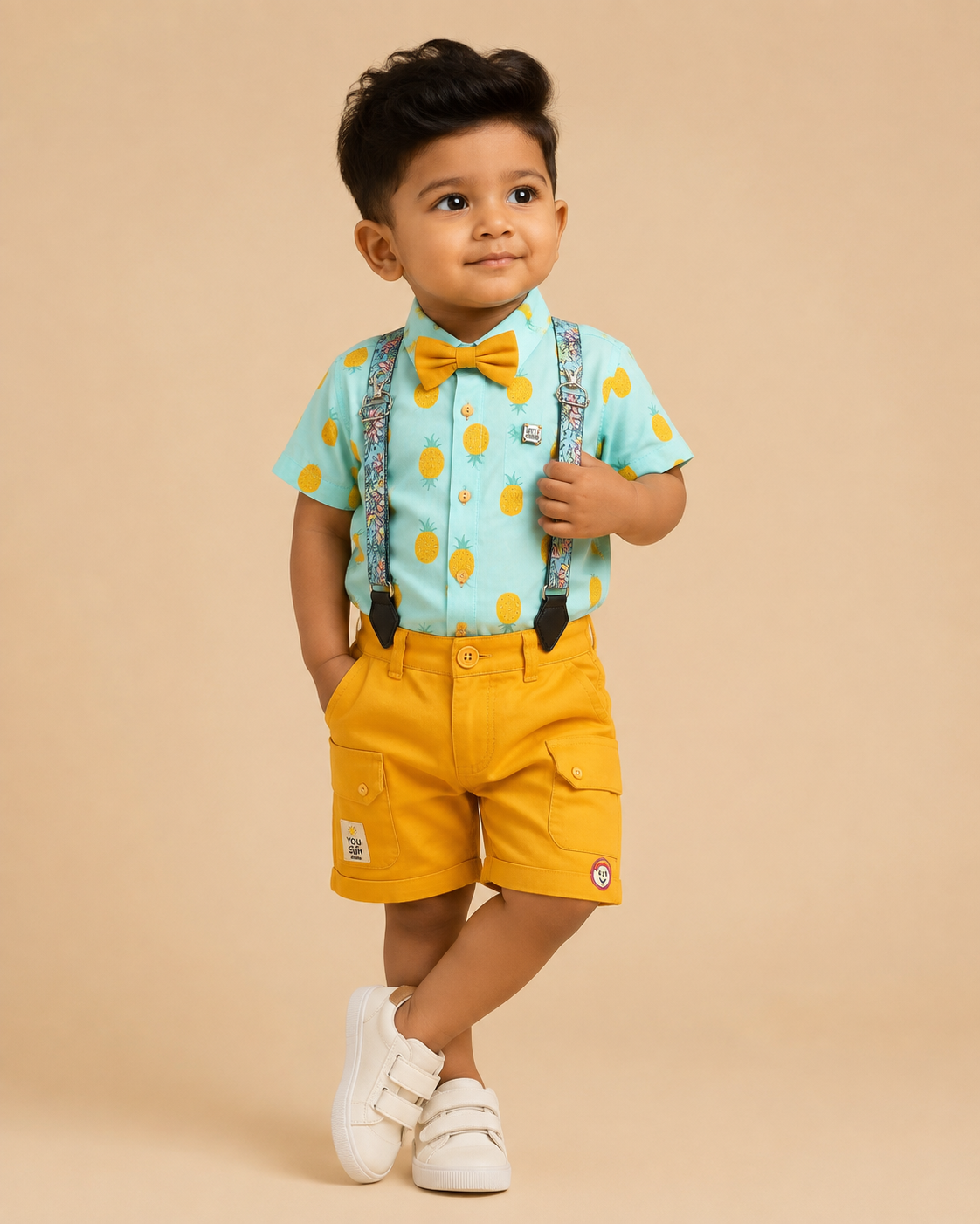 Boys attire featuring a tropical pattern button-down shirt, cargo style shorts, matching neck bow, and adjustable floral motif suspenders.