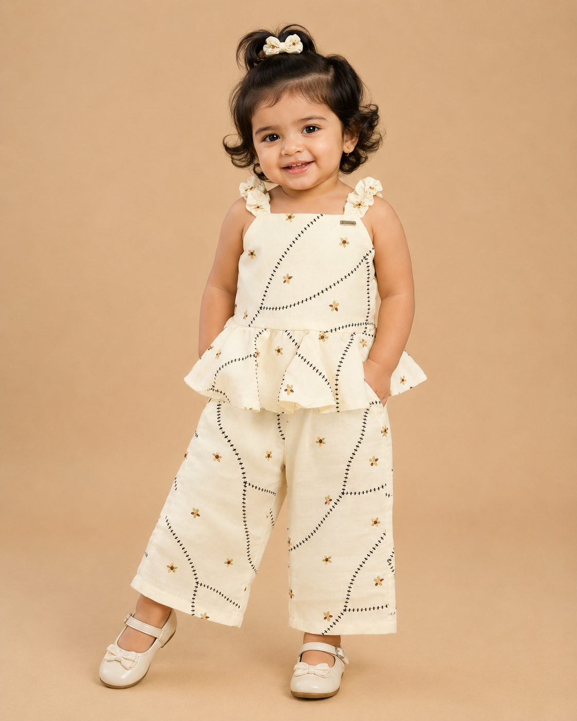 A cute patterned cotton co-ord set for baby girls featuring a sleeveless peplum top with ruffle straps and matching pants on a hanger.