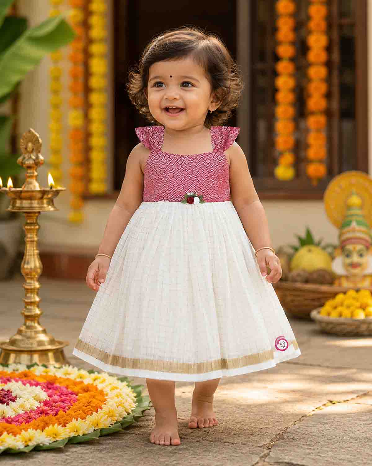 Toddler traditional ethnic wear frock with woven Kasavu pattern and floral detail for festivals.