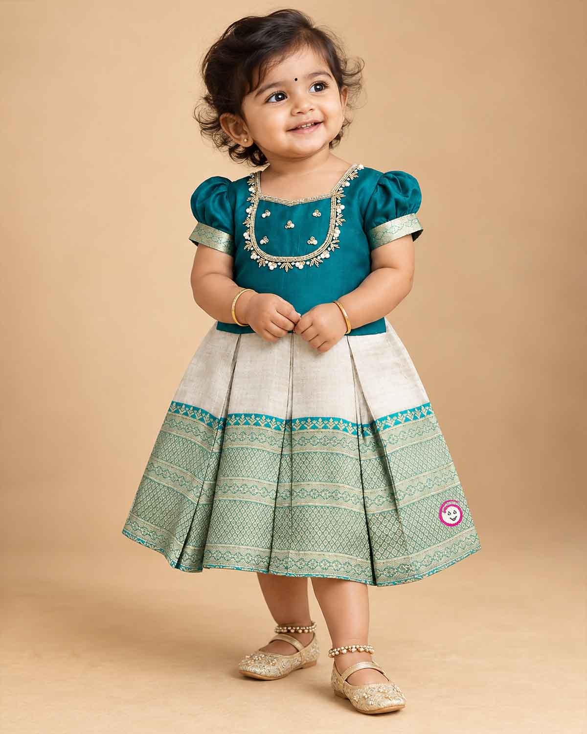 Infant silk festive frock featuring handcrafted neckline embroidery and zari woven hemline
