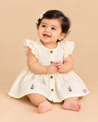 Off white infants frock with frill sleeve, front buttons, and small floral embroidery
