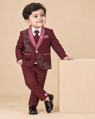 Maroon formal suit for little boys featuring a blazer with black and silver sequin details, a grey collar accent, white shirt, black tie, and matching maroon pant against a grey background.